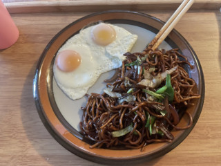 A plate containing a messy pile of chow mein and two sunny-side up eggs.